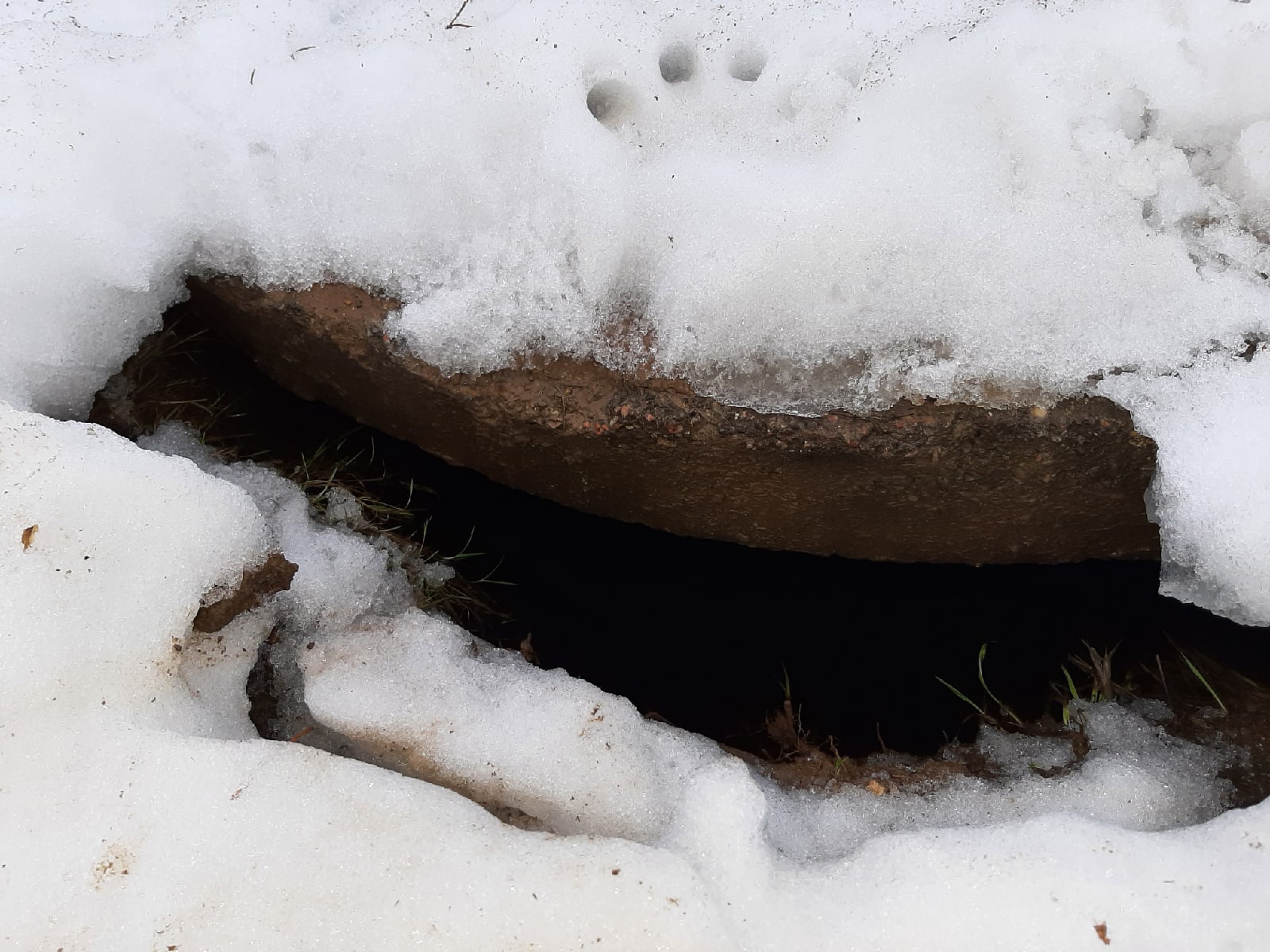 Снежные сугробы покрылись тонкой едва видимой. Открытый люк под снегом. Провал в колодец. Мужчина провалился под снег.